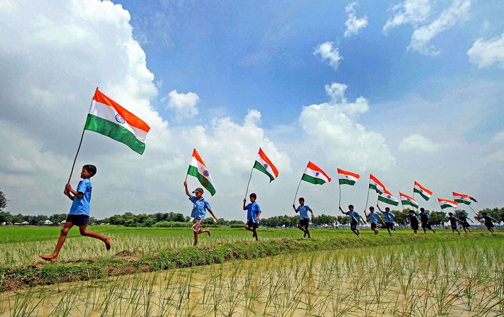 School children run with the Indian flags in a paddy field ahead of Independence Day at Parui in Birbhum district of West Bengal.