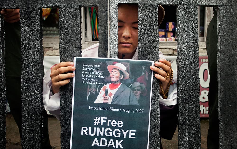 An exile Tibetan poses as Runggye Adak as he stands behind bars depicting jail during a street performance by Tibetan activists in Dharmsala. On Aug. 1, 2007, Adak, a Tibetan nomad, was arrested and is now serving eight years imprisonment in a Chinese prison on charges of making anti-Chinese government statements.