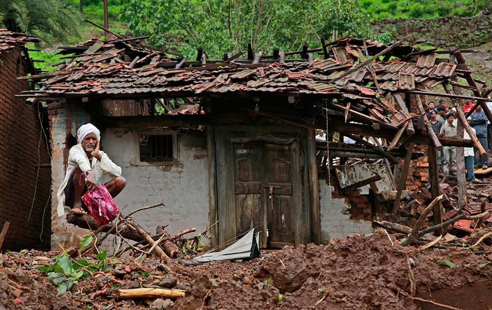 A villager watches a rescue operation sitting by his damaged house at the site of a landslide in Malin village, in the western Indian state of Maharashtra.