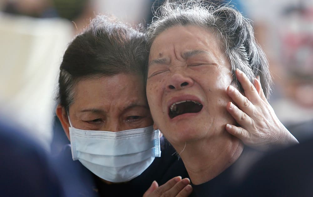 A relative, right, of a victim in the multiple explosions from an underground gas leak is consoled at a funeral parlor in Kaohsiung, Taiwan.