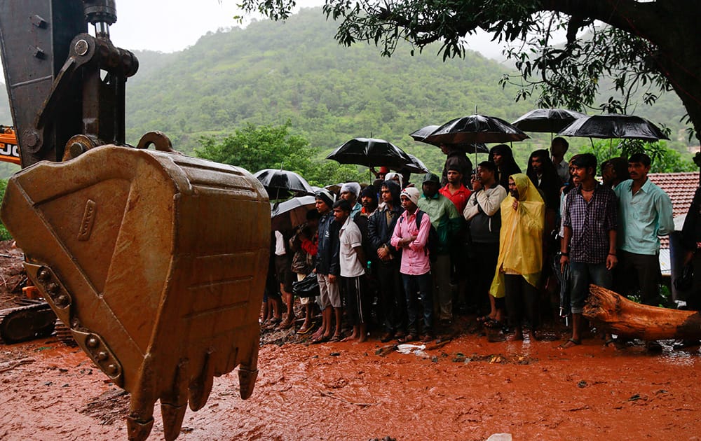 Villagers watch rescue operations at the site of a massive landslide in Malin village in Pune district of western Maharashtra state.