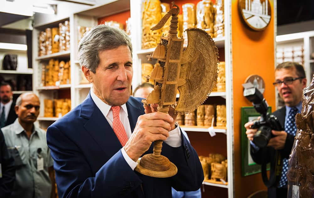 US Secretary of State, John Kerry, looks at a carved figurine during a visit to the Central Cottage Industries Emporium in New Delhi.