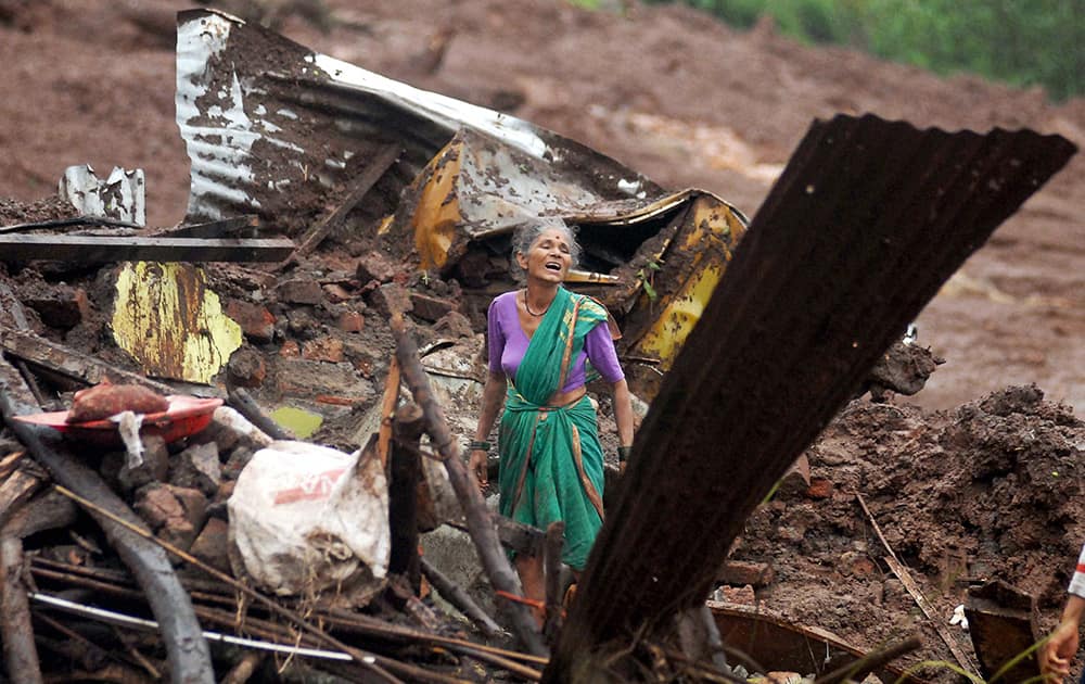 An elderly Indian woman cries as she searches for surviving family members in the debris of her home, destroyed by landslide in Malin village, in the western Indian state of Maharashtra.