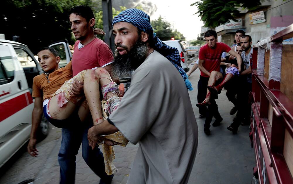 Palestinians help carry a injured people to ambulances following an Israeli Strike in Shijaiyah neighborhood, eastern Gaza City.