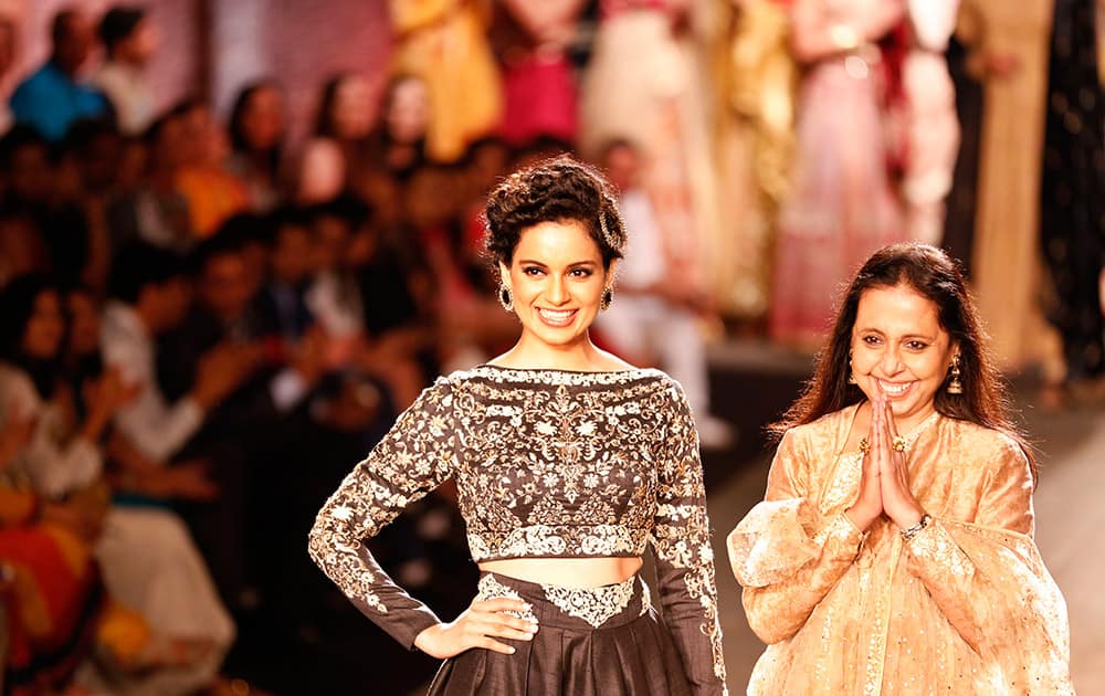 Actor Kangana Ranaut, left, displays a dress created by Indian designer Anju Modi, right, at the India Couture Week, held by Fashion Design Council of India, in New Delhi.