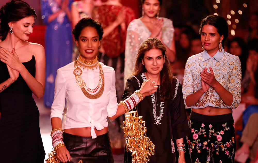 Indian designer Monisha Jaising, third from left, is led out by a model after a fashion show displaying dresses created by her at the India Couture Week, held by Fashion Design Council of India, in New Delhi.