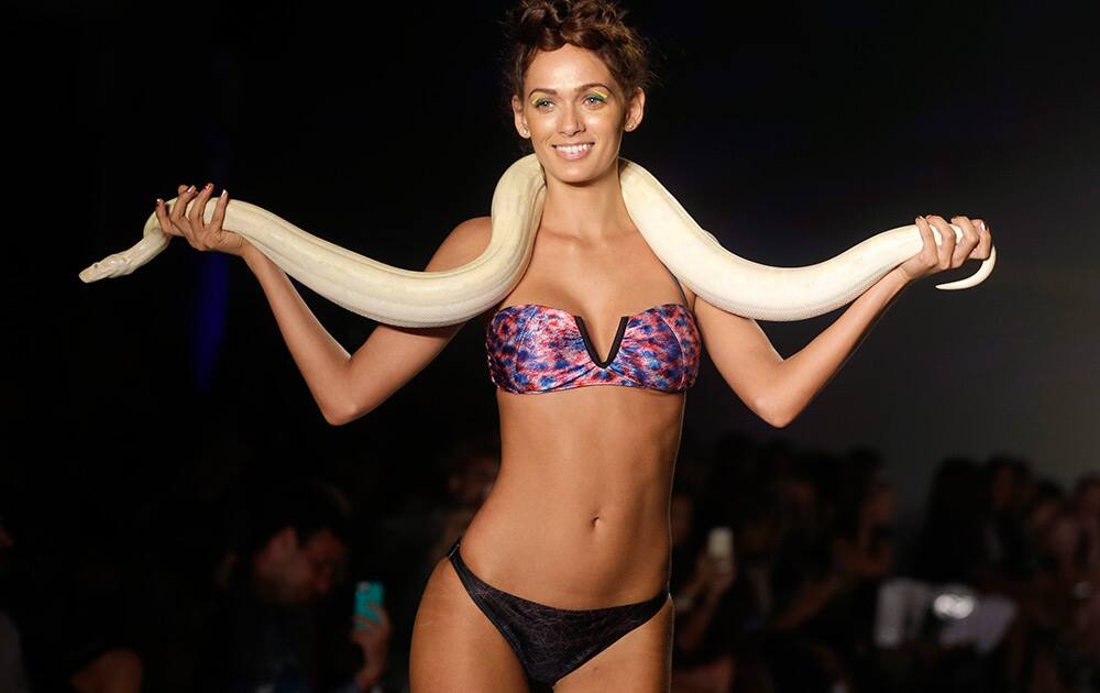 A model walks down the runway with a live snake wearing swimwear designed by We Are Handsome during the Mercedes-Benz Fashion Week Swim show in Miami Beach, Fla.