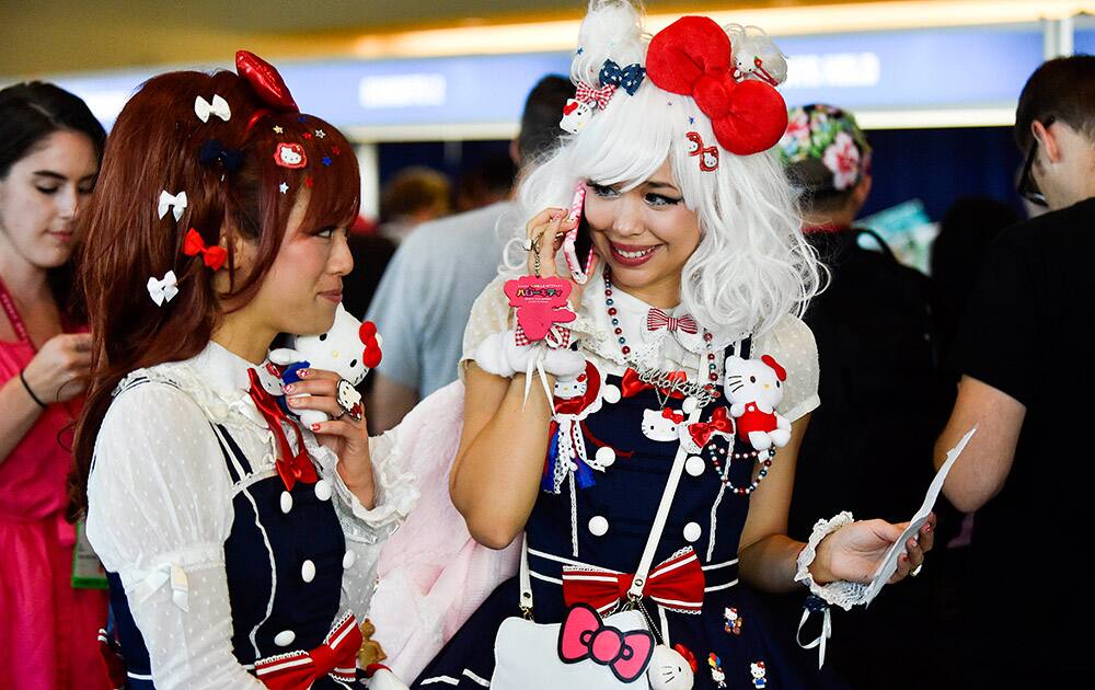 Dressed in Hello Kitty costumes, Thalia, left, and Kammie wait in line for credentials on preview night at the 2014 Comic-Con International Convention held Wednesday, July 23, 2014 in San Diego.