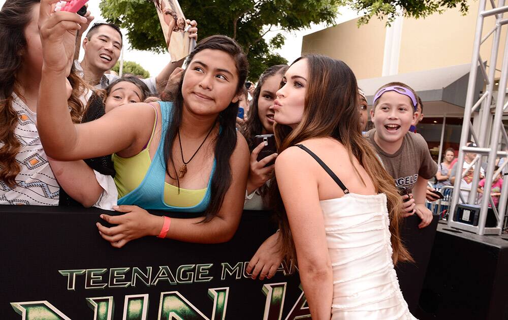 Megan Fox poses for a photo with a fan at the Los Angeles premiere of `Teenage Mutant Ninja Turtles` at the Regency Village Theater.