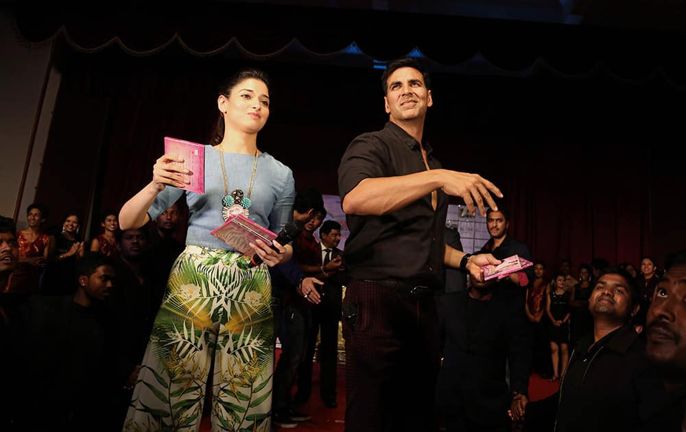 Bollywood actors Akshay Kumar, right, and Tamannaah Bhatia throw compact discs of songs from their upcoming movie 'Entertainment' during an promotional event at a college in Bangalore, India.