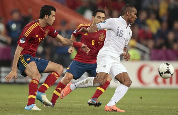 France's Florent Malouda, right, Spain's Xavi Hernandez, center, and Sergio Busquets go for a ball during the Euro 2012 soccer championship quarterfinal match between Spain and France in Donetsk, Ukraine, Saturday, June 23, 2012.