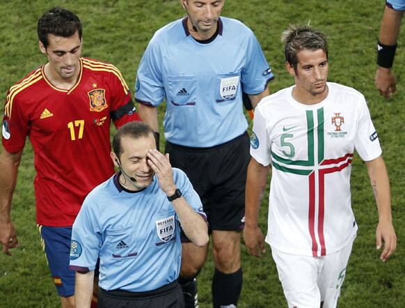 Referee Cuneyt Cakir of Turkey, second left, gestures as he leaves the pitch with Spain's Alvaro Arbeloa, left, and Portugal's Fabio Coentrao at halftime of the Euro 2012 soccer championship semifinal match between Spain and Portugal in Donetsk, Ukraine, Wednesday, June 27, 2012.