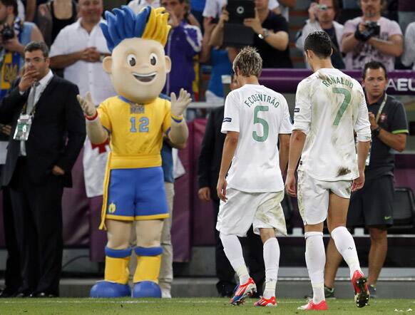 Portugal's Cristiano Ronaldo and Portugal's Fabio Coentrao leave the pitch, as one of the championship mascot Slavko applauds after the Euro 2012 soccer championship semifinal match between Spain and Portugal in Donetsk.