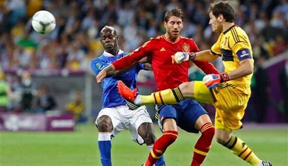 Spain goalkeeper Iker Casillas clears the ball in front of Italy's Mario Balotelli, left and Spain's Juanfran Torres during the Euro 2012 soccer championship final between Spain and Italy in Kiev, Ukraine.