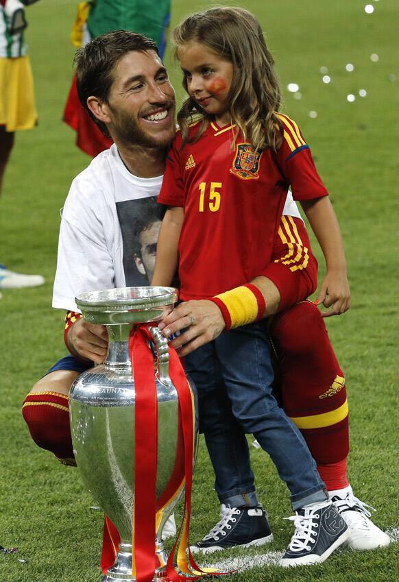 Spain's Sergio Ramos, left, holds the trophy with a girl after the Euro 2012 soccer championship final between Spain and Italy in Kiev, Ukraine.