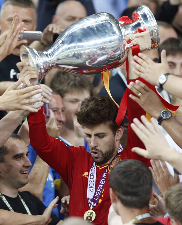 Spain's Gerard Pique holds up the trophy through supporters after the Euro 2012 soccer championship final between Spain and Italy in Kiev, Ukraine.