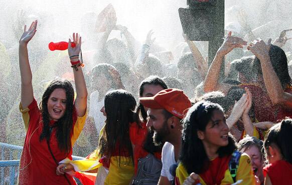 Firemen, unseen, spray water on Spanish fans as they celebrate Spain's Euro 2012 soccer championship in Madrid.