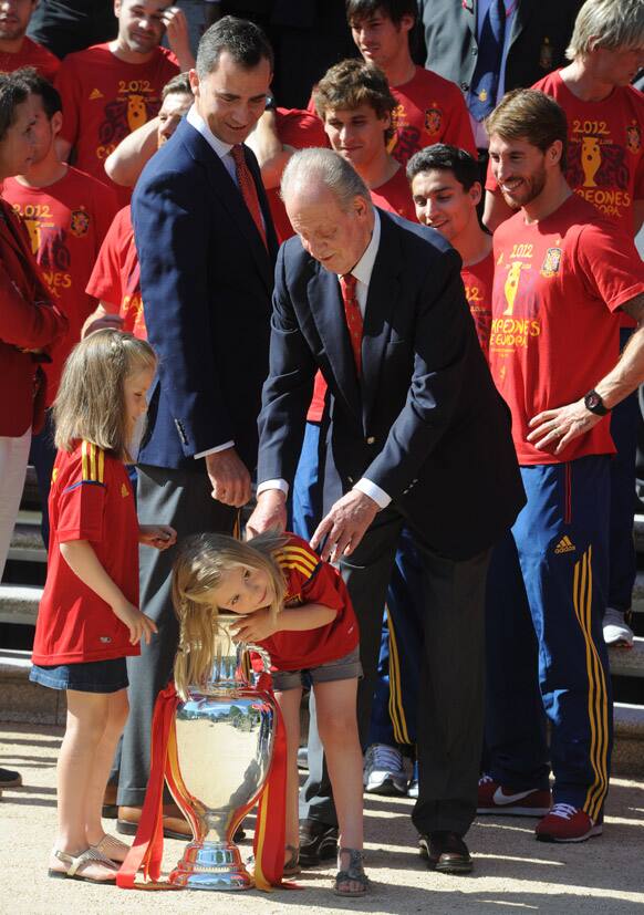 Spain's King Juan Carlos and Crown Prince Felipe watch Spain's Princess Sofia as she puts her arm into the Euro 2012 trophy next to Princess Leonor during a visit by the national soccer team members to the Zarzuela Palace in Madrid.