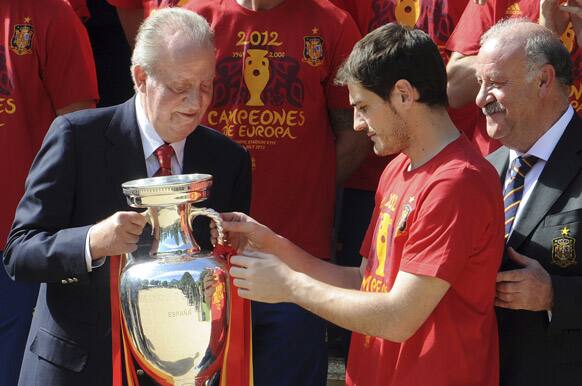 Spain's national soccer team captain Iker Casillas gives the Euro 2012 trophy to Spain's King Juan Carlos, watched by coach Vicente del Bosque at the Zarzuela Palace in Madrid, a day after winning the trophy by beating Italy in the final in Kiev.