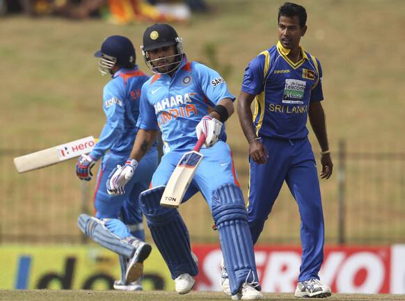 Sri Lanka's bowler Nuwan Kulasekara, right, watches India's, Virat Kohli, center, and Virender Sehwag, left, running between the wickets during the first one-day international cricket match between Sri Lanka and India.