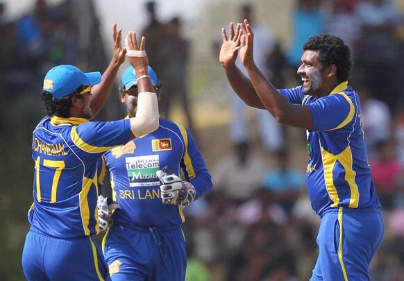 Thisara Perera, right, celebrates the dismissal of India's batsman Suresh Raina, unseen, with Dinesh Chandimal, left, and Kumar Sangakkara, center, during the second one-day international cricket match between Sri Lanka and India in Hambantota.