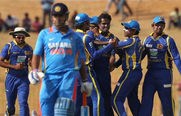 Angelo Mathews, third right, celebrates with teammates as India's captain Mahendra Singh Dhoni, second left, walks back to the pavilion after his dismissal during the second one-day international cricket match between Sri Lanka and India in Hambantota.