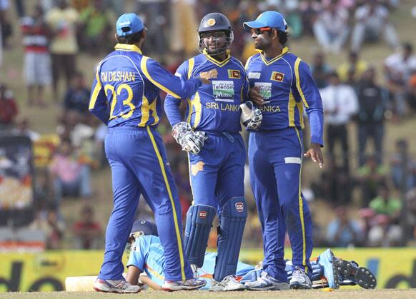 Ravichandran Ashwin lies on the ground after unsuccessfully diving to avoid a run out as Sri Lanka's cricketers, Tillakaratne Dilshan, Kumar Sangakkara, and Lahiru Thirimanne celebrate during the second one-day international cricket match between Sri Lanka and India in Hambantota.