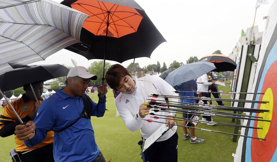 South Korea's Im Dong-hyun, right, inspects his arrows on the target next to Taiwan's Kuo Cheng-Wei, in blue, during an individual ranking round at the 2012 Summer Olympics in London.