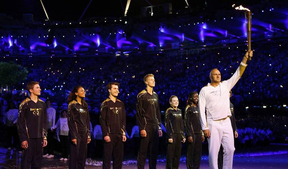 Steve Redgrave, right, holds the Olympic torch after entering the stadium during the Opening Ceremony at the 2012 Summer Olympics in London.