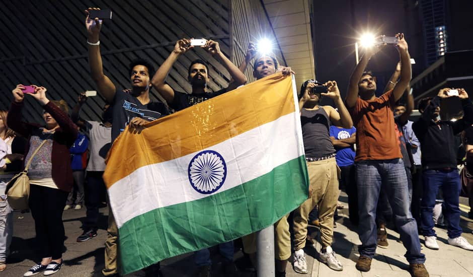 Men hold the national flag of India as they take photographs of fireworks from a neighborhood outside the Olympic Park during the 2012 Summer Olympics Opening Ceremony in London. 