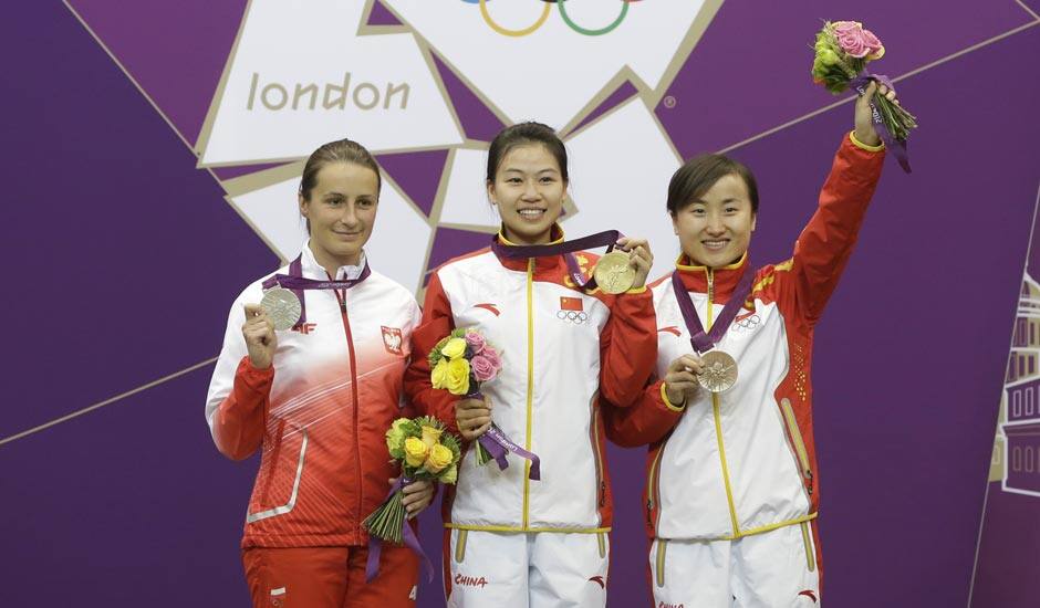 China's Yi Siling, center, celebrates winning the gold medal in the women's 10-meter air rifle event, alongside silver medalist Poland's Sylwia Bogacka, left, and bronze medalist China's Yu Dan, right, at the 2012 Summer Olympics.