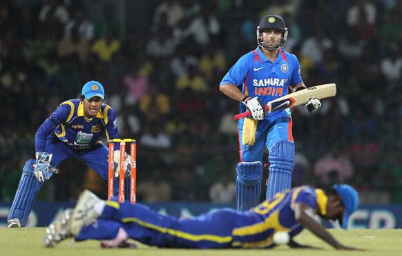 Sri Lanka's Angelo Mathews, foreground lies on the ground after diving to hold a ball as India's batsman Virat Kohli, right and Sri Lanka's wicket keeper Dinesh Chandimal, left watch during the third one-day international cricket match between India and Sri Lanka in Colombo.