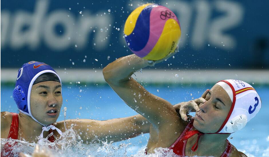 Ma Huanhuan of China, attempts to block a shot by Anna Espar Llaquet of Spain during their women's water polo preliminary round match at the 2012 Summer Olympics in London.