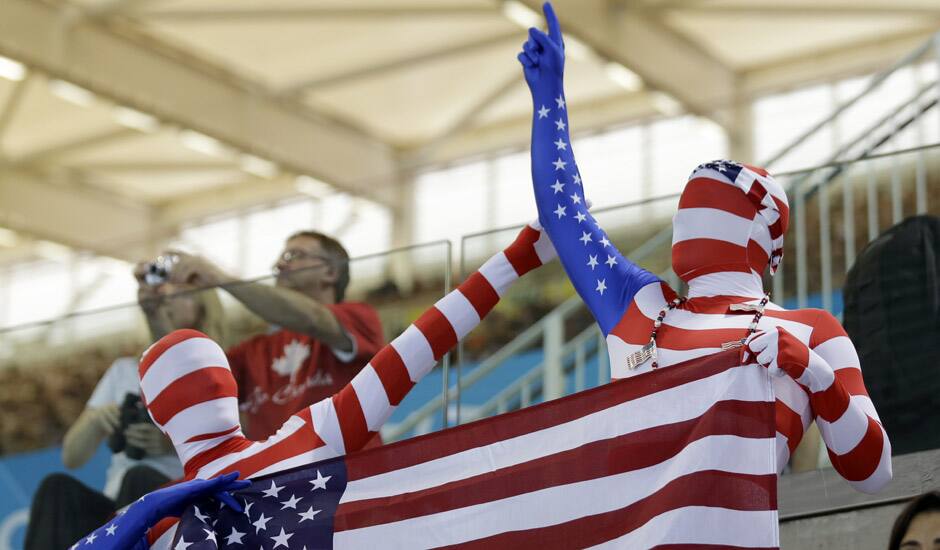 Fans dressed in costumes in the colors of the U S flag watch swimming competitions at the Aquatics Centre in the Olympic Park during the 2012 Summer Olympics in London.