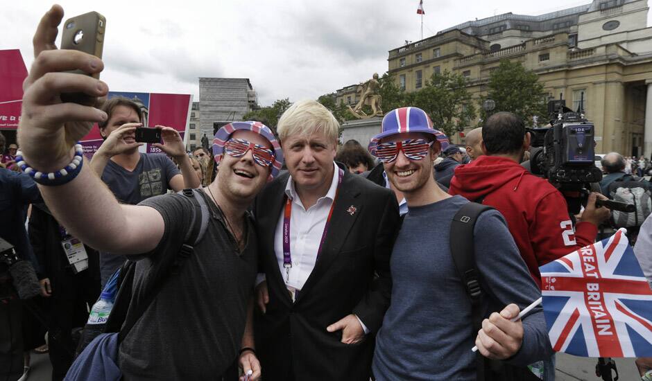 London Mayor Boris Johnson, poses for pictures with Britain team fans, following a photo-op with London ambassadors, the volunteers working around the city to give tourists directions and information, in central London.