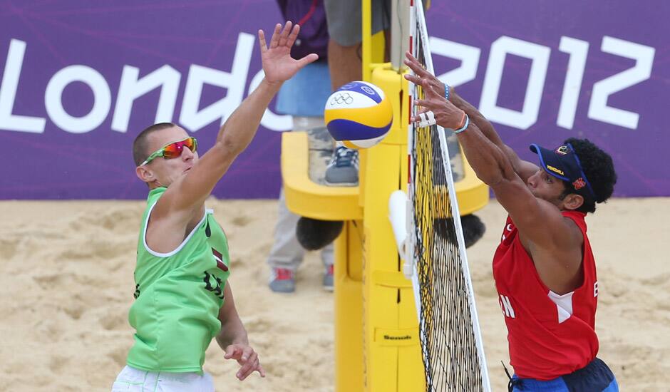 Martins Plavins, from Latvia spikes a ball past Igor Hernandez, from Venezuela during their Beach Volleyball match at the 2012 Summer Olympics in London.