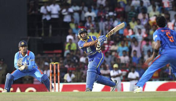 Sri Lanka's batsman Lasith Malinga, center, bats as India's captain Mahendra Singh Dhoni, left, and bowler Manoj Tiwary, right, watch during the fourth one-day international cricket match between India and Sri Lanka in Colombo.