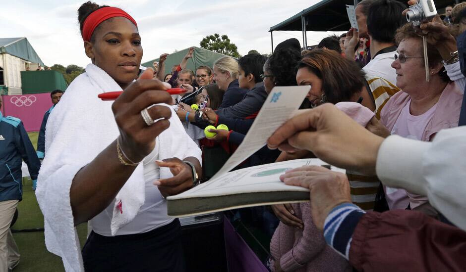 Serena Williams of the United States signs autographs after a doubles match at the All England Lawn Tennis Club in Wimbledon, London at the 2012 Summer Olympics.