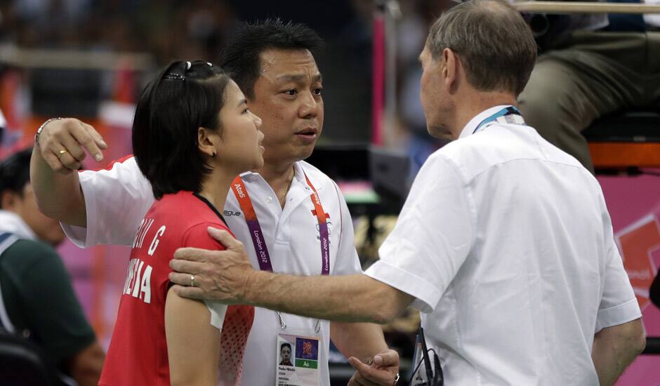 Head badminton referee Torsten Berg talks to Indonesia's Greysia Polii and her coach Paulus Firman, after he showed a black card to players in the women's doubles badminton match in London.