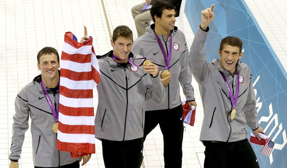 United States swim team members, from left, Ryan Lochte, Conor Dwyer, Ricky Berens and Michael Phelps walk with a U.S. flag after being awarded the gold medal for their win in the men's 4 x 200-meter freestyle relay at the Aquatics Centre in the Olympic Park during the 2012 Summer Olympics in London