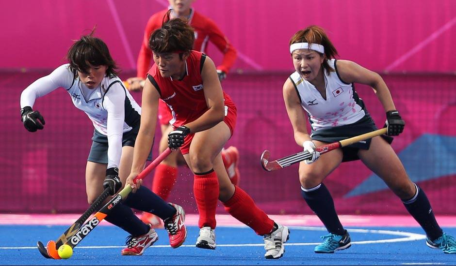 South Korea's Park Mi-Hyun and Japan's Yukari Yamamoto, vie for the ball as Japan's Nagisa Hayashi, looks on in the women's hockey preliminary round match at the 2012 Summer Olympics.