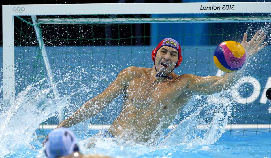 Nikolay Maximov of Kazakhstan makes a save on a shot by Greece during a preliminary men's water polo match at the 2012 Summer Olympics.