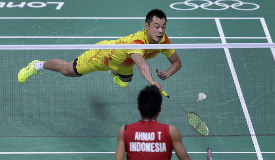 China's Xu Chen dives to return a shuttle while playing against Indonesia's Tontowi Ahmad, and Liliyana Natsir, unseen, at a mixed doubles badminton semifinal match of the 2012 Summer Olympics.