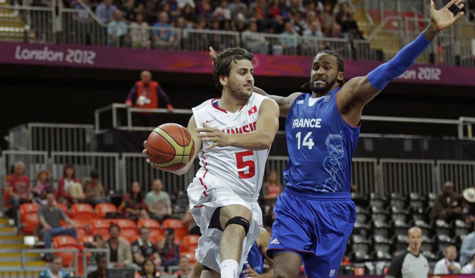 Tunisia's Marouan Laghnej, looks to pass as he drives past France's Ronny Turiaf during a men's basketball game at the 2012 Summer Olympics in London. 