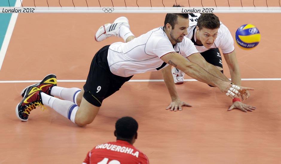 Germany's Gyorgy Grozer (9, left) and Lukas Kampa (11) dive for a shot by Tunisia's Anouer Taouerghi (12) during a men's volleyball preliminary match at the 2012 Summer Olympics.