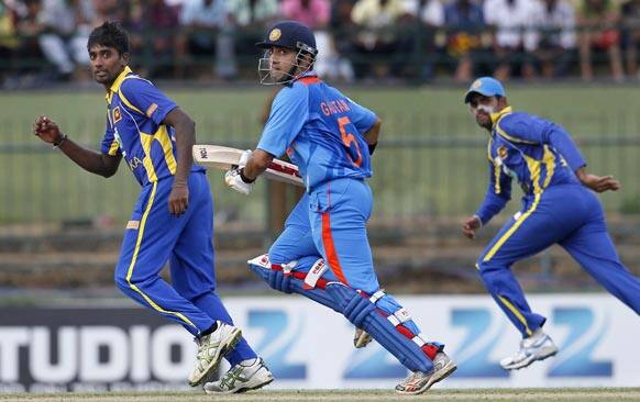 Gautam Gambhir, center, runs between the wickets as Sri Lanka's Nuwan Pradeep, left, and Lahiru Thirimanne, right, run to hold the returning ball during their fifth one day international cricket match in Pallekele..