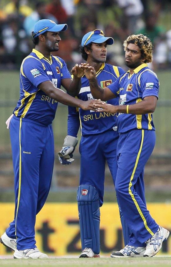 Sri Lanka's bowler Lasith Malinga, right, celebrates the dismissal of India's batsman Manoj Tiwary, unseen, with Thisara Perera, left, and Dinesh Chandimal, center, during their fifth one day international cricket match in Pallekele.