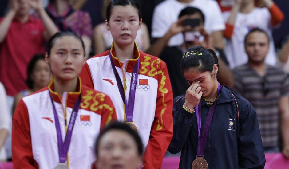 India's Saina Nehwal, right, fights back tears as she stands at themedal podium for winning bronze in women's singles badminton of the 2012 Summer Olympics.