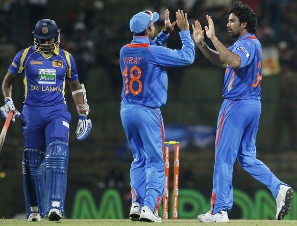 Zaheer Khan, right, celebrates the dismissal of Sri Lanka's batsman Chamara Kapugedera, left, with Virat Kohli, center, during the fifth one day international cricket match between India and Sri Lanka in Pallekele.