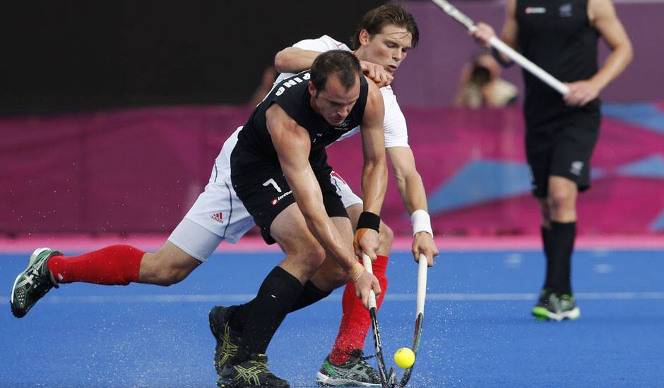 Belgium's Felix Denayer and New Zealand's Blair Hopping, front, battle for the ball in the men's hockey preliminary round match at the 2012 Summer Olympics.